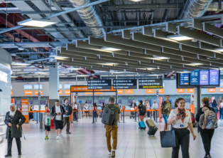 Check-in hall with passengers and information boards at London Luton Airport - luton Airport Taxi